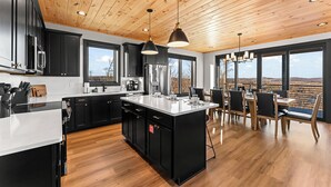 Une cuisine moderne dotée d’un îlot central, de meubles de rangement noirs et d’un revêtement de sol en bois.