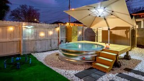 Ein Whirlpool mit Baldachin, umgeben von einem Holzzaun und einer kleinen Terrasse.