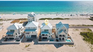 Una proprietà fronte spiaggia con diversi edifici, una piscina e una spiaggia sullo sfondo.