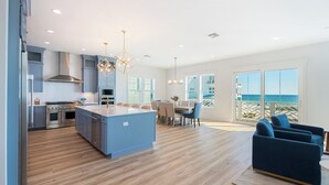 Una cucina moderna con isola centrale, zona pranzo con vista e soggiorno con vista.