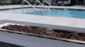 Área de piscina com recurso de água e churrasqueira a carvão.
