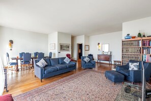 A spacious living room with a blue sofa set, a patterned rug, and a bookshelf filled with books. - Piazza Rossetti 3A/8, Genova, Italy (Genova)