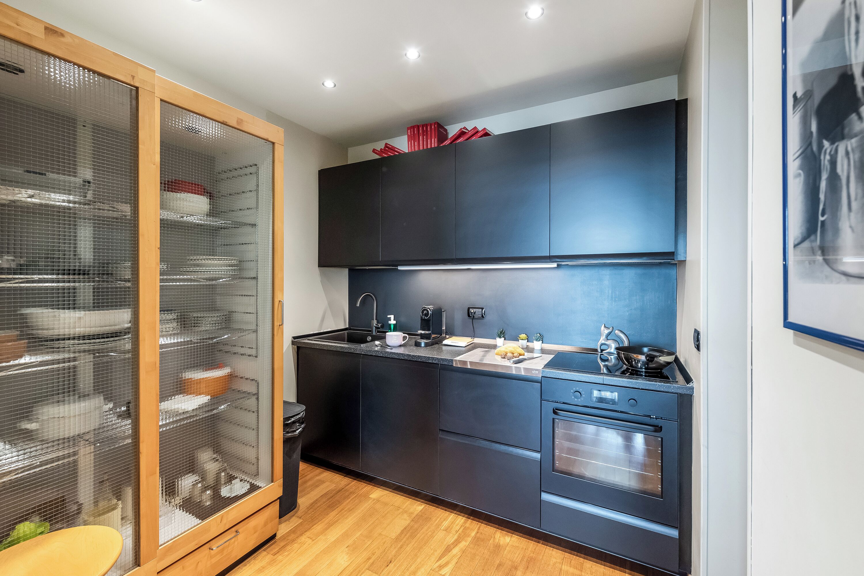 Eine moderne Küche mit schwarzer Arbeitsplatte, Edelstahlgeräten und einem Schrank mit Glastür.