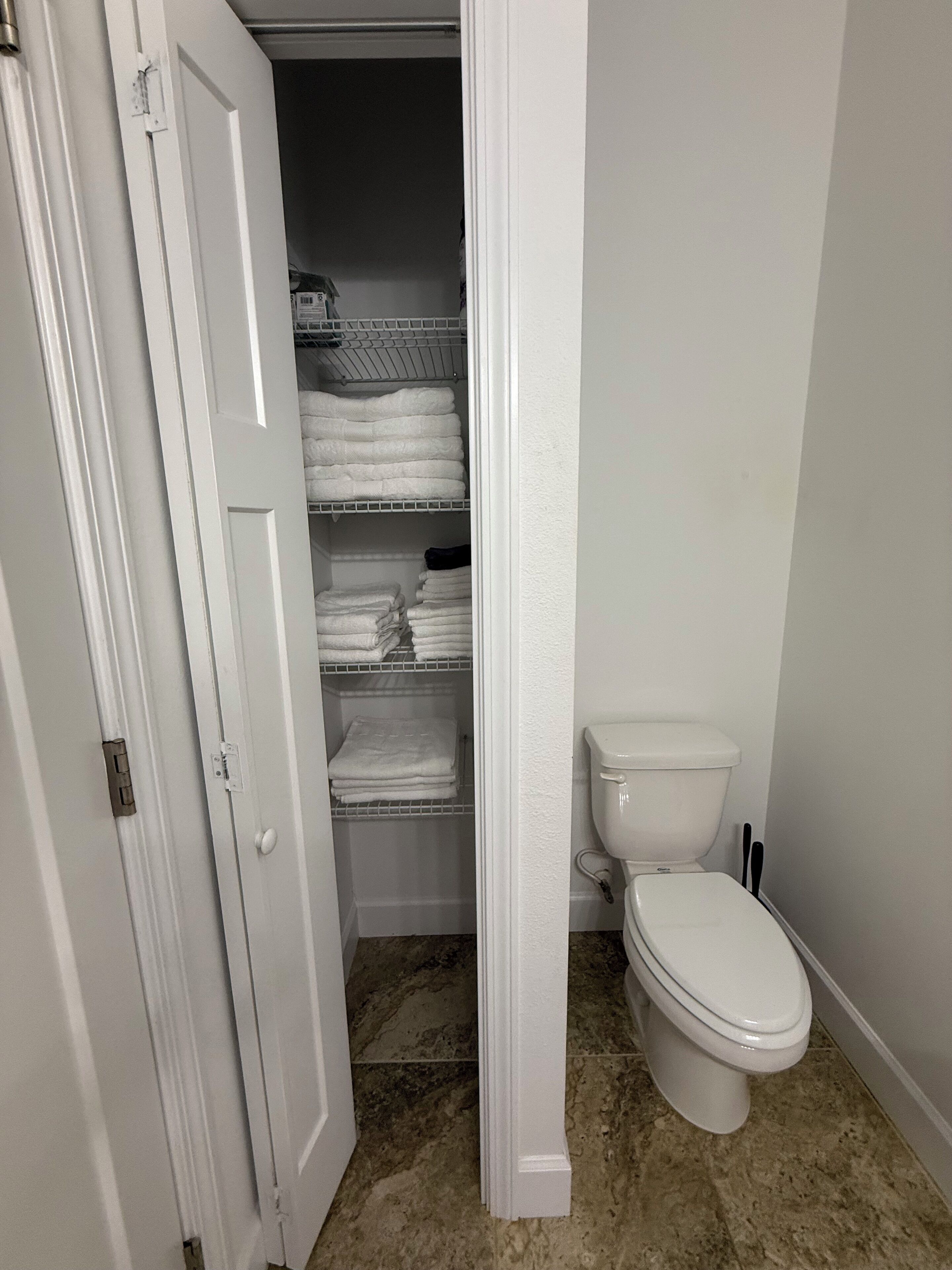 Un baño con inodoro, toallero con toallas dobladas y suelo de mármol.