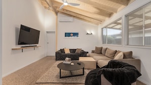Ein modernes Wohnzimmer mit einem Flachbildfernseher, zwei Sofas, einem Couchtisch und einem Deckenventilator.