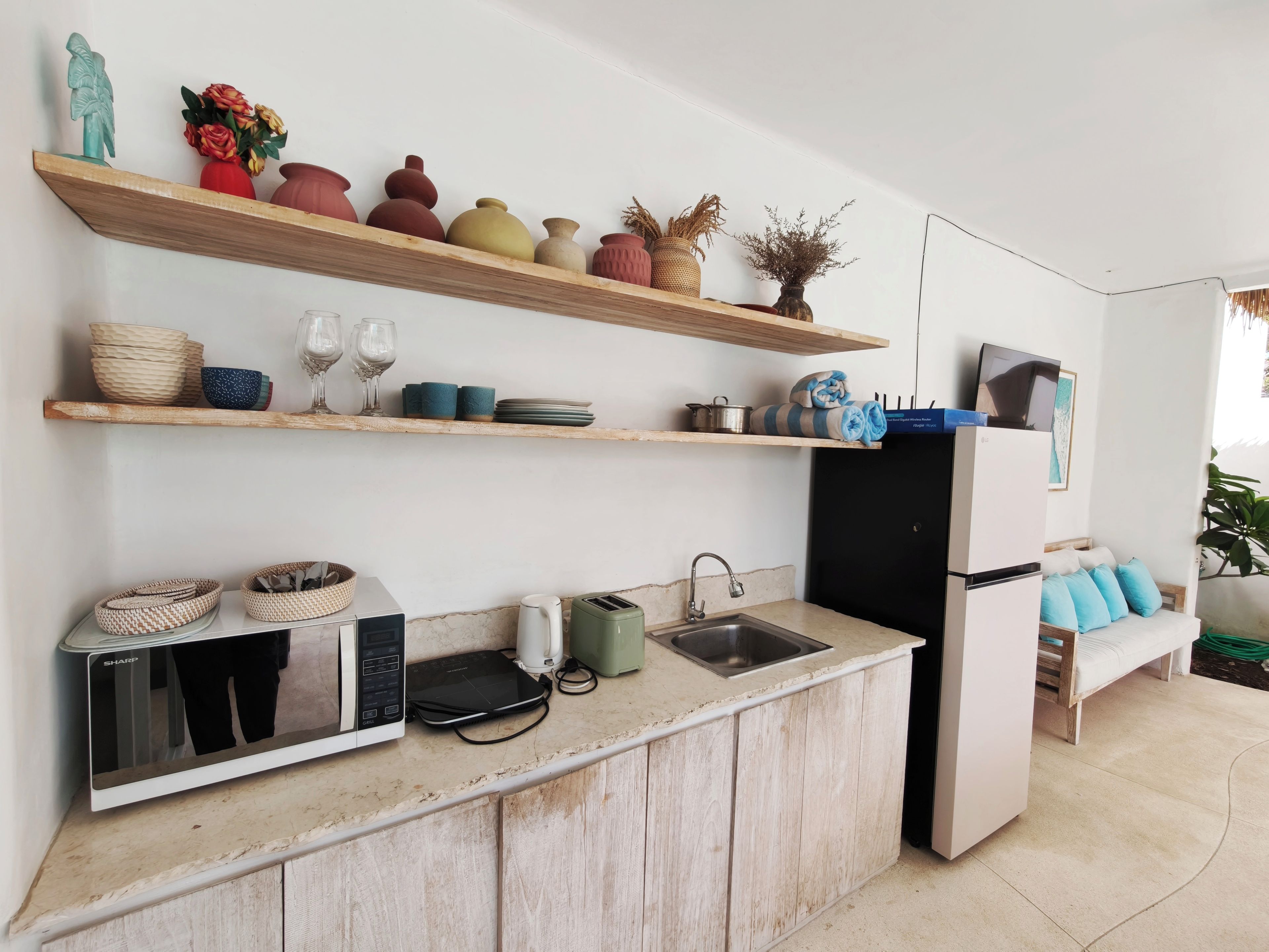 Una cocina moderna con estantes de madera, microondas integrado y refrigerador.