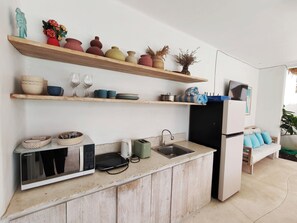 Una cocina moderna con estantes de madera, microondas integrado y refrigerador.