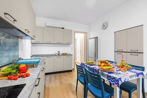 Eine moderne Küche mit Essbereich, ausgestattet mit einem eingebauten Ofen, einer Spüle und einem für eine Mahlzeit gedecktem Esstisch.