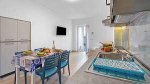 A compact kitchen with a dining area, a flat-screen TV, and a modern stove. - Merlo A -  Center & Private Parking, Ceriale, Italy (Ceriale)