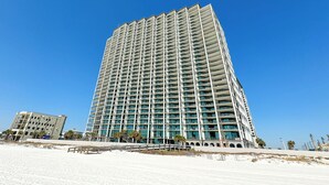 Een hoog hotel met meerdere balkons, uitzicht op het strand en een modern architectonisch ontwerp.