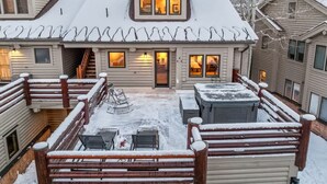 Una cabana de fusta amb un porxo cobert, una banyera d'hidromassatge i un teulat cobert de neu.
