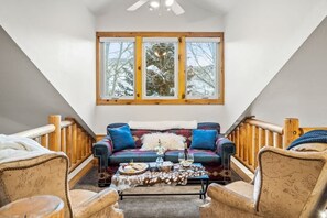 A cozy room with a sofa, chairs, a table with drinks, and a large window with a view of trees. - Abode at Crestview, private hot tub, minutes to Deer Valley (Park City)