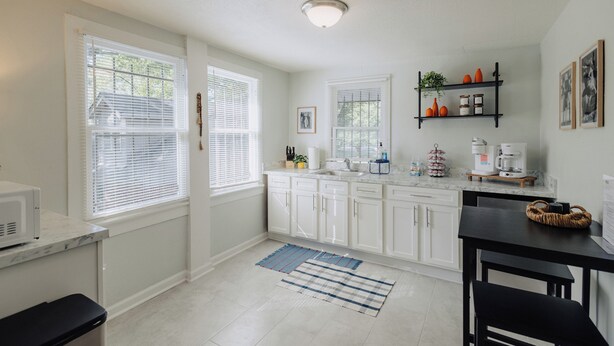 A modern kitchen with white cabinetry, a marble countertop, and a black dining table. - Centrally Located King Bed Midtown Liberty 2695 UP (Memphis)