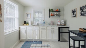 A modern kitchen with white cabinets, a black refrigerator, and a coffee maker on the counter. - Centrally Located King Bed Midtown Liberty 2695 UP (Memphis)