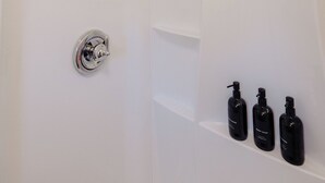 A bathroom with a shower, a toilet, and three black bottles on a shelf. - Centrally Located King Bed Midtown Liberty 2695 UP (Memphis)
