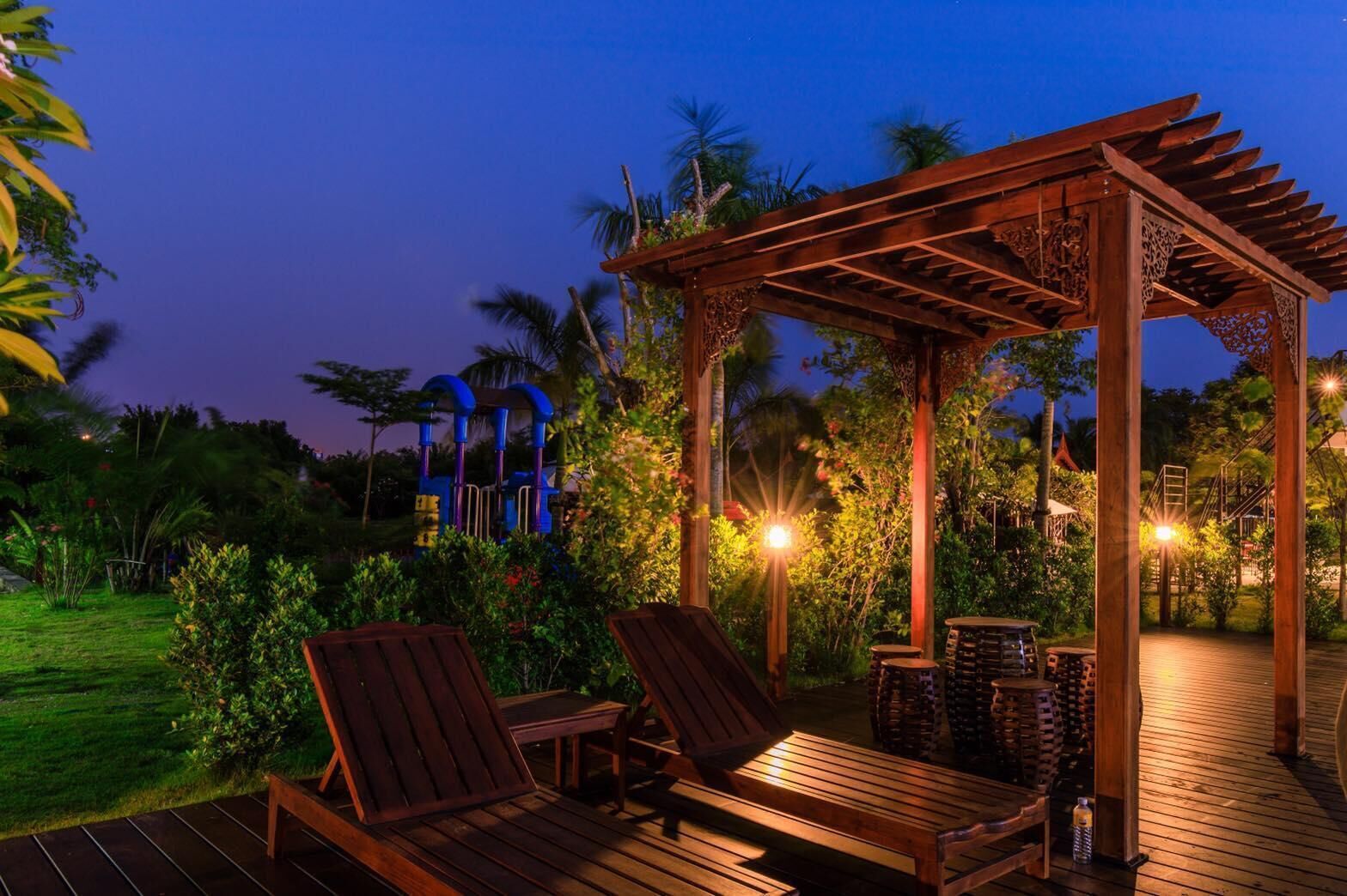 A wooden deck with two lounge chairs and a pergola with intricate woodwork.