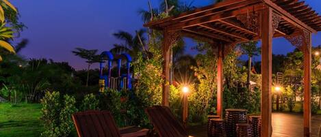 A wooden deck with two lounge chairs and a pergola with intricate woodwork.