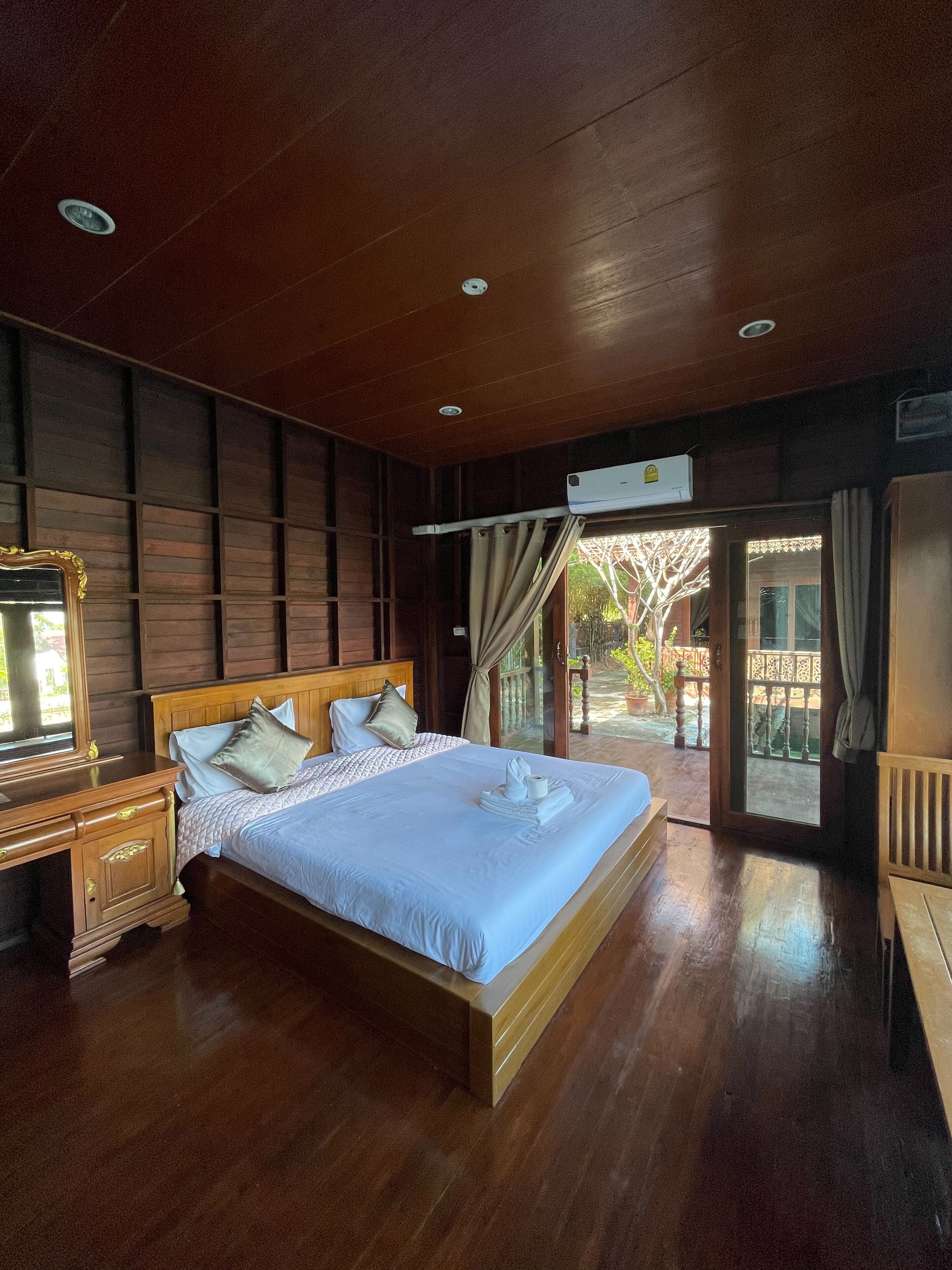 A spacious bedroom with a large bed, wooden headboard, and a nightstand.