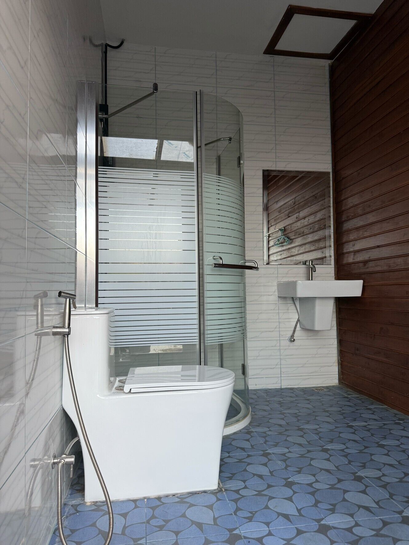 A modern bathroom with a glass-enclosed shower, a white toilet, and a sink.