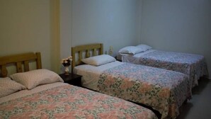 A room with two single beds, each with floral bedding and wooden headboards.