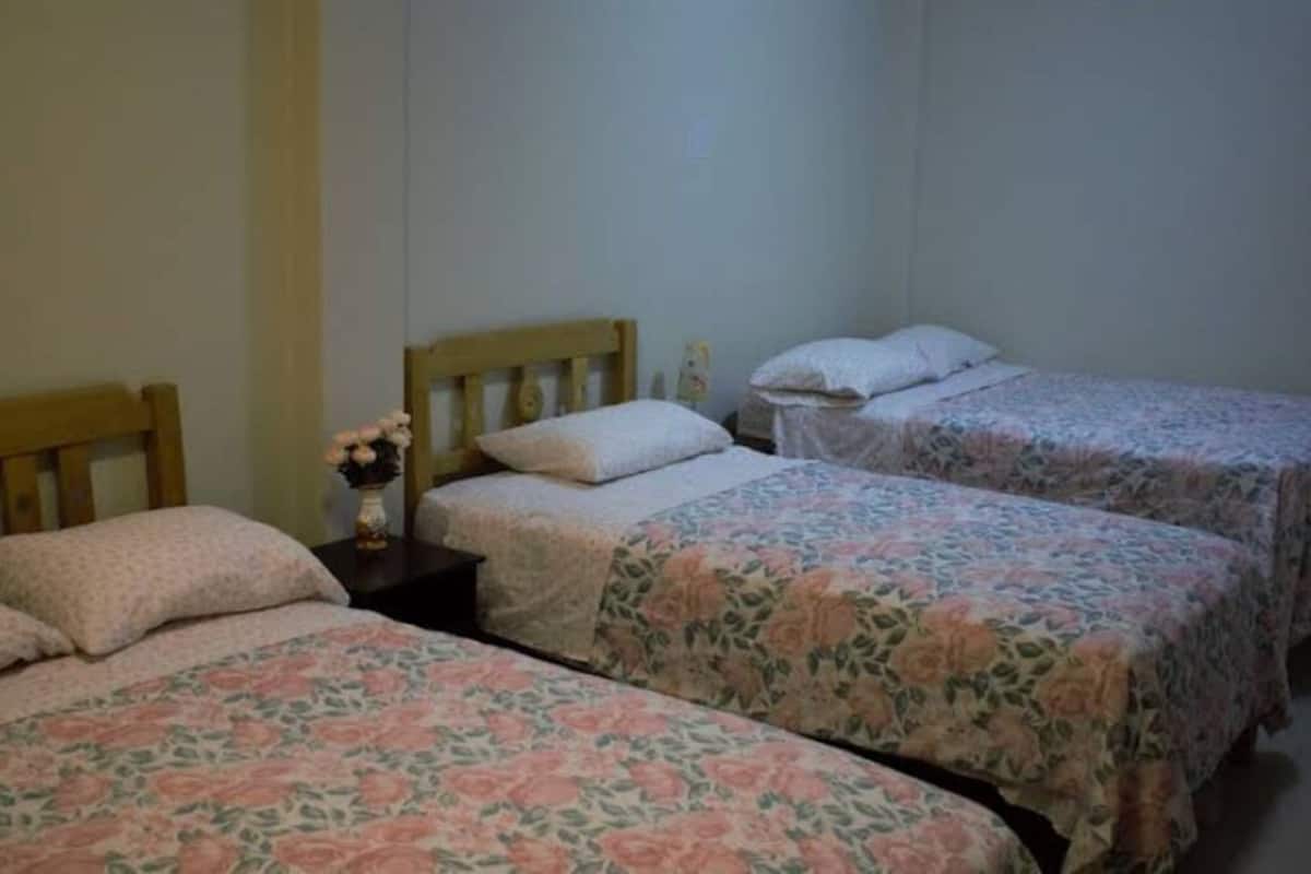 A room with two single beds, each with floral bedding and wooden headboards.