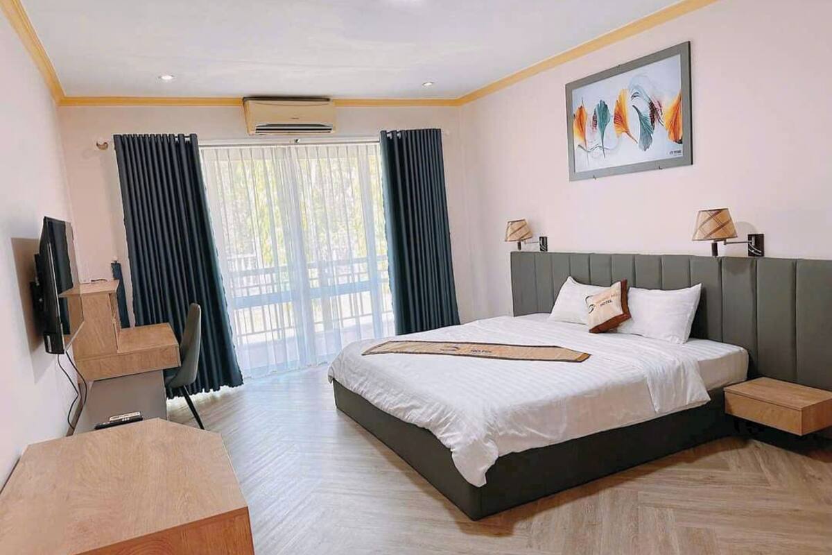 Una habitación de hotel moderna con una cama grande, un escritorio y una televisión.