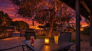 Eine Terrasse im Freien mit Tisch, Stühlen, einer Kerze und einem Getränk.