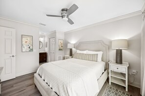 Ein Schlafzimmer mit einem großen Bett, Deckenventilator, Nachttischlampen und einem Nachttisch.