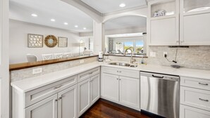 A modern kitchen with white cabinetry, a stainless steel dishwasher, and a marble backsplash. - Oceanfront Pet-Friendly Retreat w/ Private Courtyard (Fernandina Beach)
