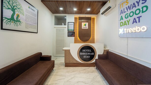 A hotel reception desk with a sign reading "HOTEL SHRIDHAR STAY" and a tree-themed artwork on the wall. - Treebo Shridhar Stay, 2.6 Km From Indore Junction (Indore)