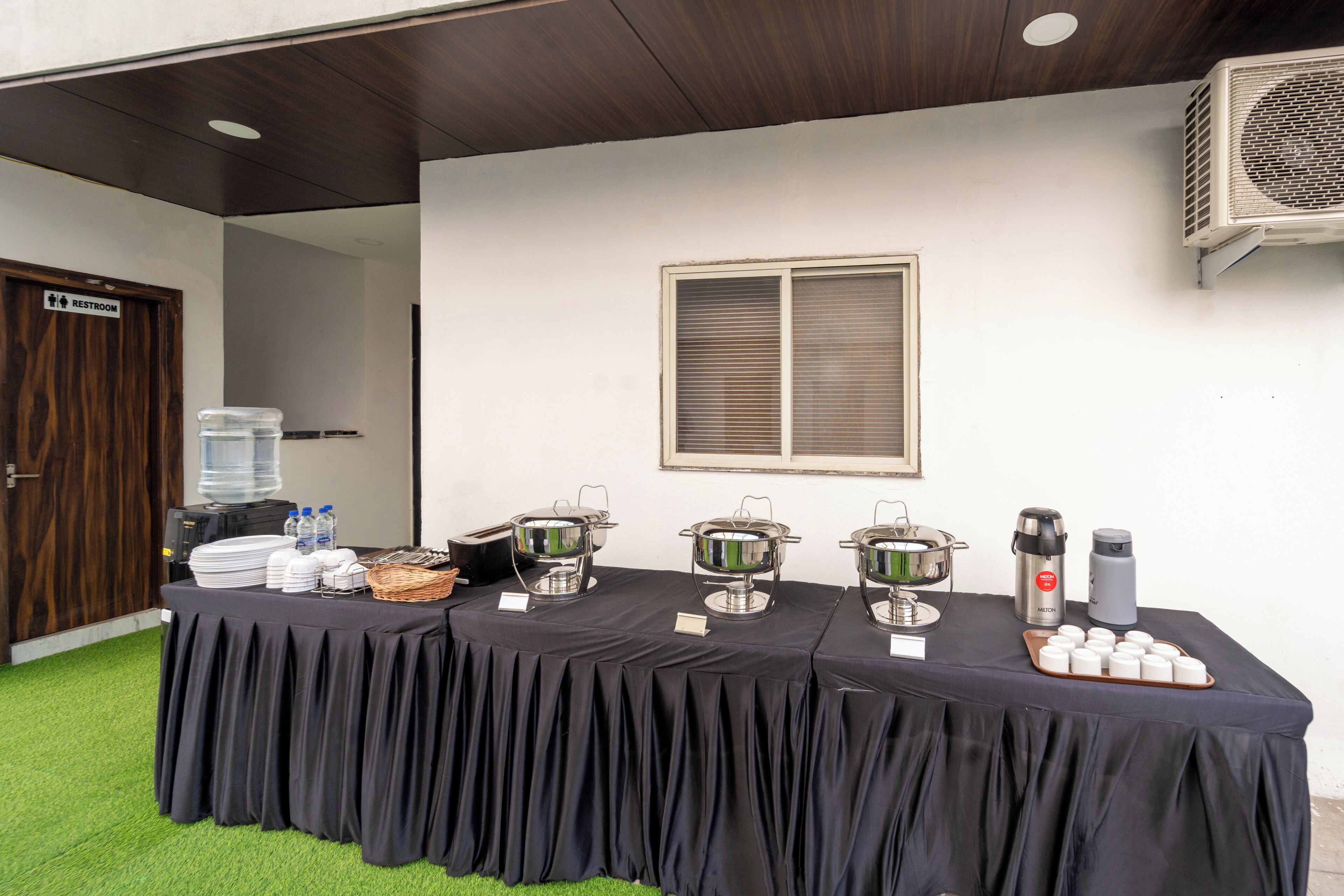 A buffet table with food containers, a water dispenser, and a coffee maker.