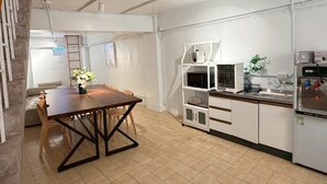 A compact kitchen with a dining table, white cabinets, and a built-in microwave. -  Anlan Residence Hotel Cultural Road Pavilion in Jietu, Orange Wood Hidden Garden (Chiayi City)
