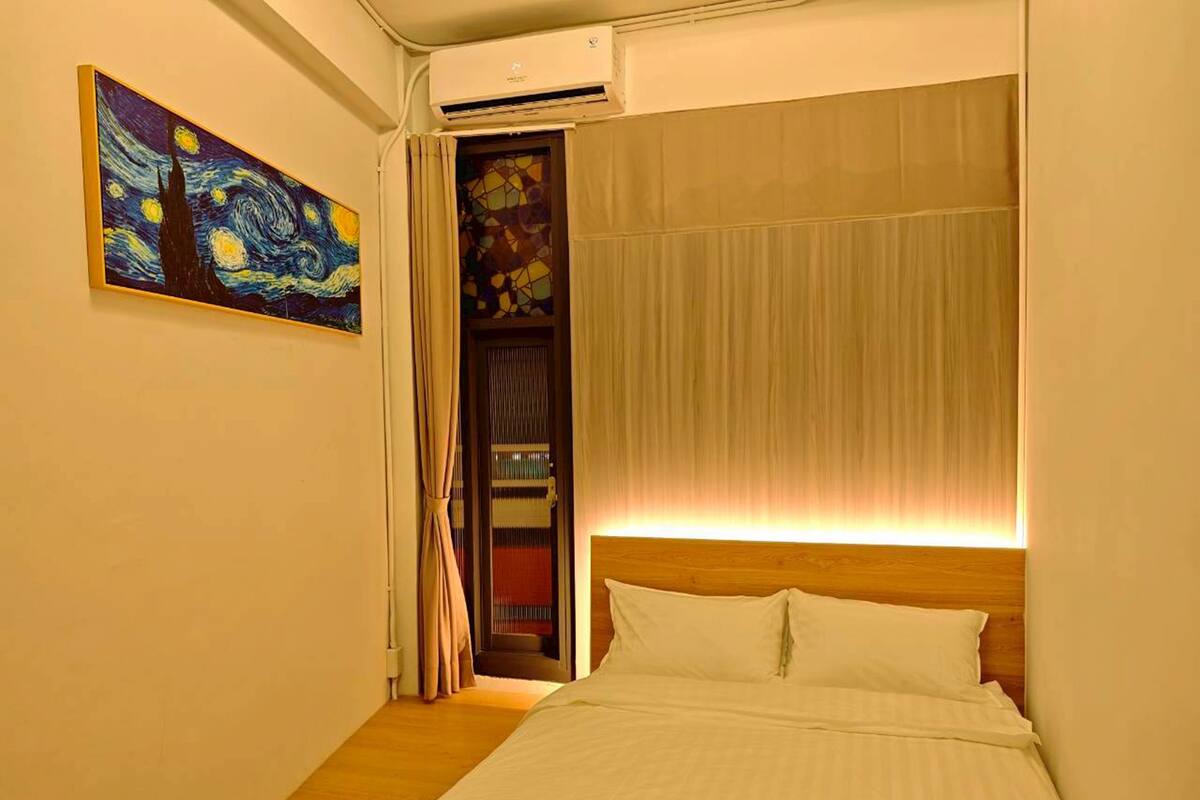 Ein Schlafzimmer mit Bett, einem Bild, einer Tür und einer Klimaanlage.