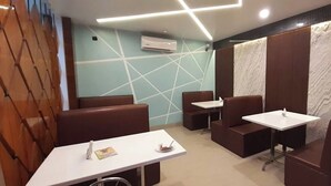 Ein modernes Restaurant mit Sitzecken und weißen Tischen.