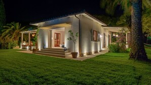 Une maison moderne dotée d’un patio couvert, d’une cheminée en pierre et d’une pelouse bien entretenue.