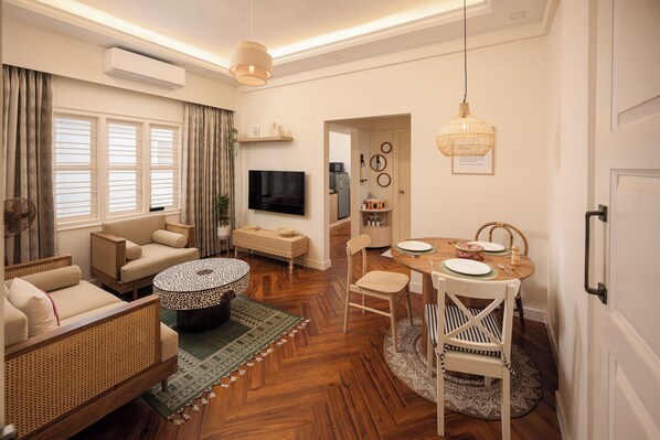 A modern living room with a sofa, a round coffee table, and a dining area with a table and chairs. - Hoodo Zoe (Bengaluru)