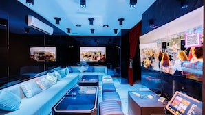 Un salon moderne avec un canapé, une table basse et un grand écran diffusant un concert.