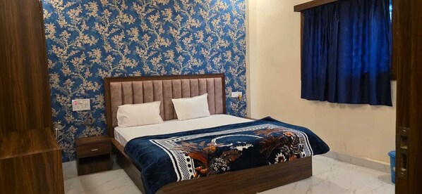 Un dormitorio con cama, cabecero de madera, papel tapiz floral y cortina azul.
