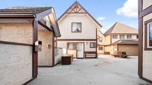 Un quartier résidentiel où les maisons sont dotées de toits à pignons et où se trouve un bâtiment central avec une porte et des fenêtres.