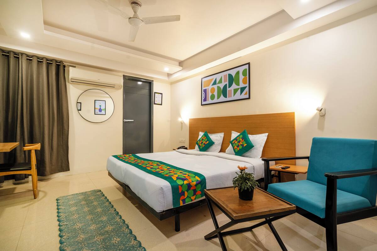 A hotel room with a bed, a desk, a chair, a small table, and a ceiling fan.