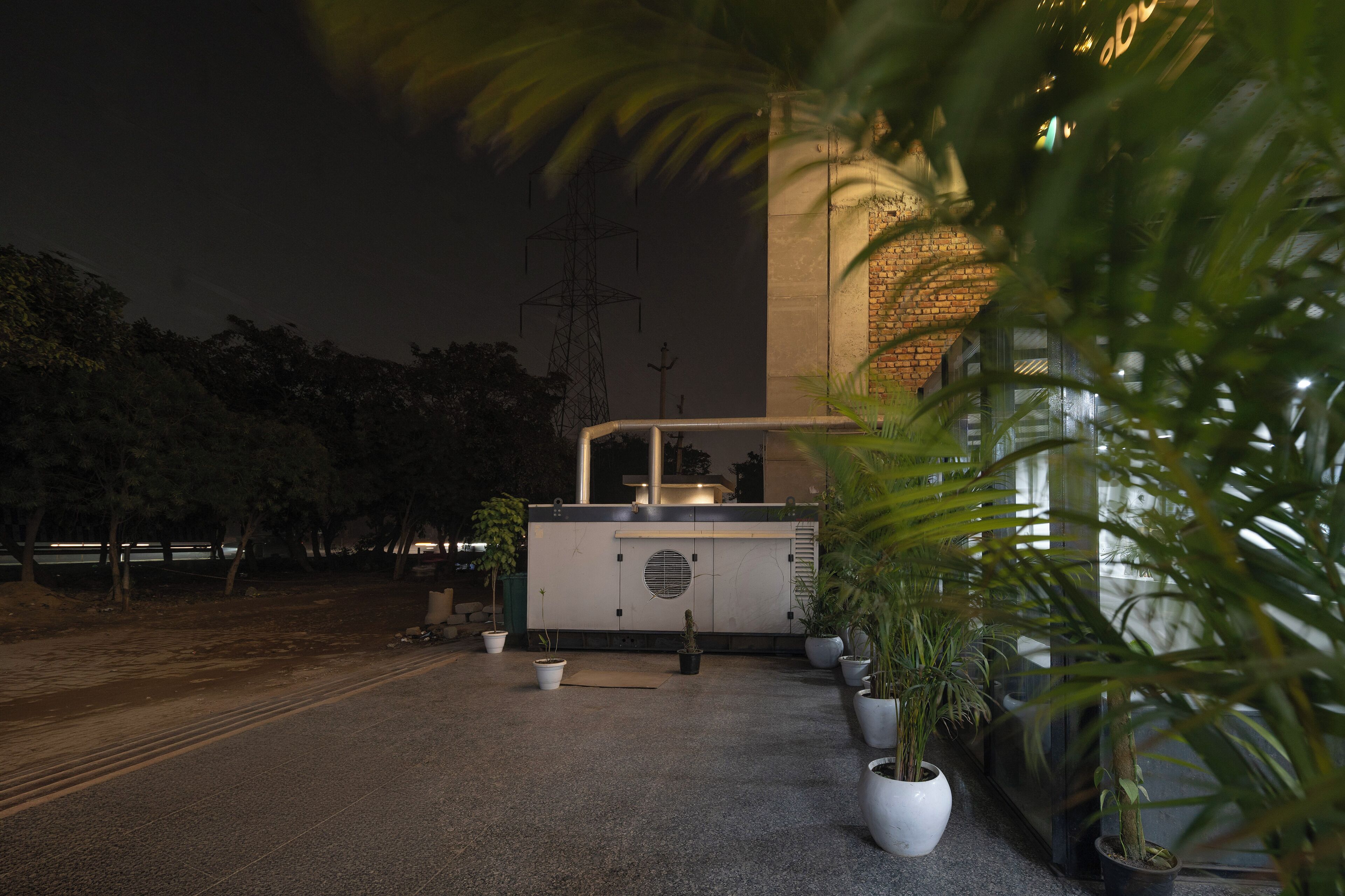 An outdoor area with a food kiosk, potted plants, and a brick wall in the background.