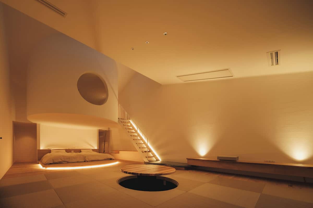 Un interior moderno con una cama, un área de descanso circular y una escalera.