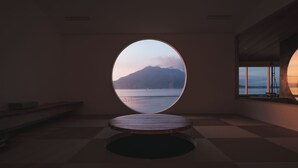 A minimalist room with a large circular window overlooking a body of water and mountains. - Good Fellows Resort (Kagoshima)