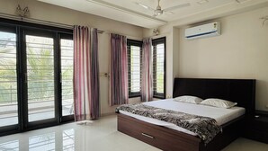 A bedroom with a bed, curtains, a ceiling fan, and an air conditioning unit.