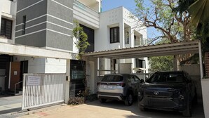 A gated parking area with two cars parked, a building with a modern design, and a pergola structure.