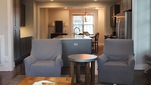 Una cocina moderna con armarios oscuros, una isla central y un área de comedor con sillas.