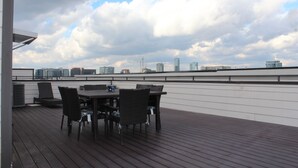 Terraza en la azotea con una mesa y sillas, con vistas al horizonte de la ciudad.