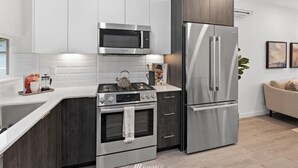 A modern kitchen with white cabinetry, stainless steel appliances, and a built-in oven.