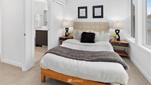 A modern bedroom with a large bed, two bedside tables with lamps, a headboard, and a window.