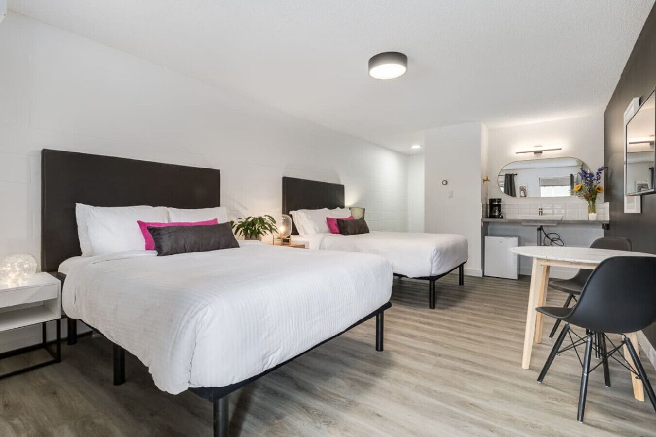 Une chambre d’hôtel avec deux lits, un bureau et une kitchenette.
